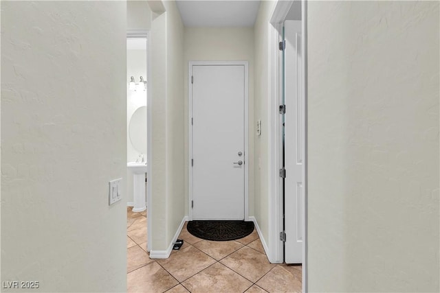 entryway with light tile patterned flooring, a textured wall, and baseboards