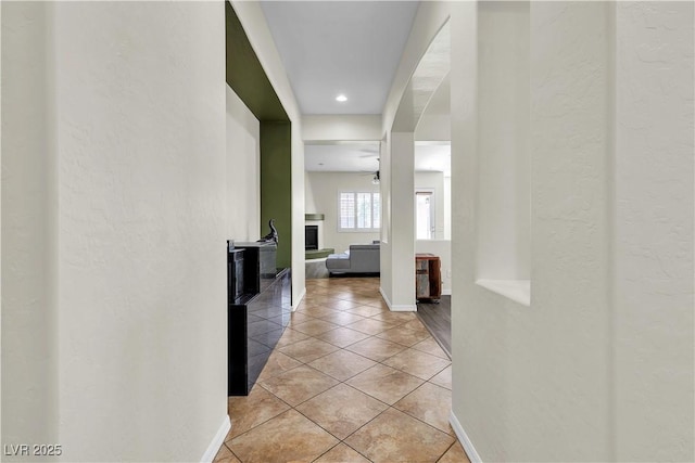hall featuring light tile patterned floors, baseboards, and recessed lighting