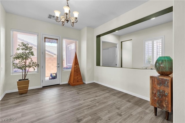 foyer entrance featuring a chandelier, wood finished floors, and baseboards