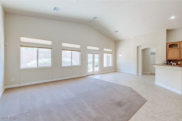 unfurnished living room featuring arched walkways, light tile patterned floors, baseboards, high vaulted ceiling, and recessed lighting