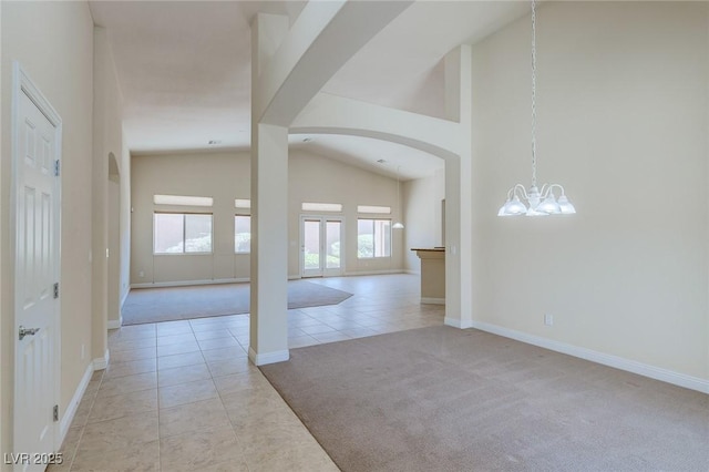 foyer entrance with arched walkways, light tile patterned flooring, a chandelier, baseboards, and high vaulted ceiling