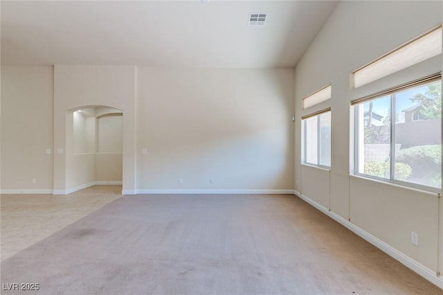 empty room with carpet, arched walkways, and baseboards