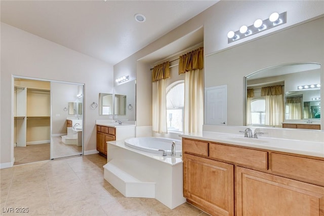 1963 Dakota Lodge Ave, Las Vegas, NV 89123 - full bathroom with vaulted ceiling, a garden tub, two vanities, tile patterned flooring, and baseboards