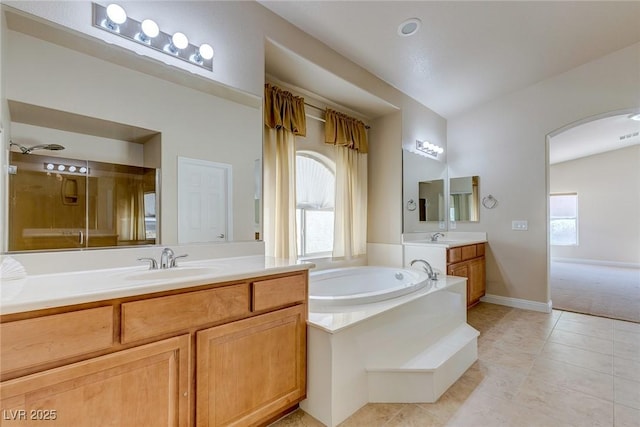 full bath with plenty of natural light, a garden tub, two vanities, and tile patterned flooring