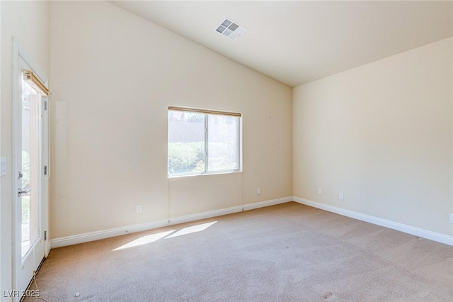 empty room with lofted ceiling, light carpet, plenty of natural light, and baseboards