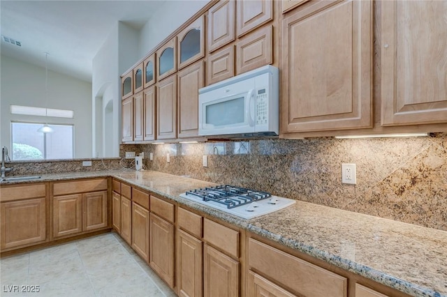 kitchen featuring white appliances, decorative backsplash, and light stone counters