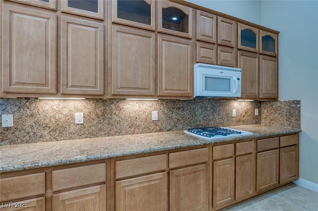 kitchen featuring white appliances, light brown cabinetry, and light stone countertops