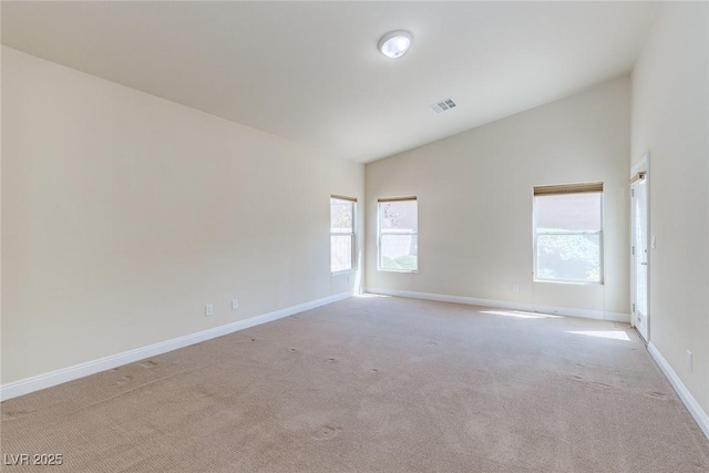 carpeted spare room featuring baseboards and lofted ceiling