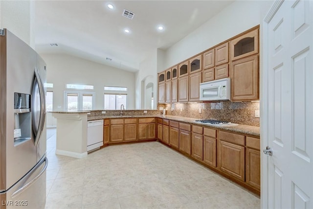 1963 Dakota Lodge Ave, Las Vegas, NV 89123 - kitchen featuring white appliances, lofted ceiling, glass insert cabinets, backsplash, and a peninsula