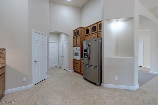 1963 Dakota Lodge Ave, Las Vegas, NV 89123 - kitchen with stainless steel fridge with ice dispenser, arched walkways, oven, brown cabinets, and glass insert cabinets