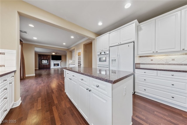 7438 Desertscape Ave, Las Vegas, NV 89178 - kitchen featuring white oven, ornamental molding, a center island, decorative backsplash, and dark wood-style flooring
