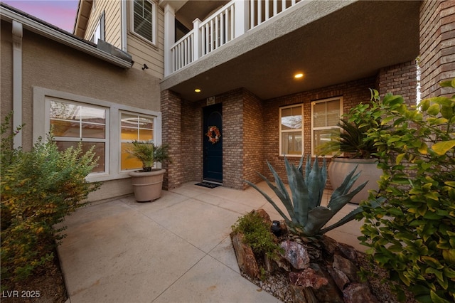 7438 Desertscape Ave, Las Vegas, NV 89178 - exterior entry at dusk with a balcony, a patio, brick siding, and stucco siding