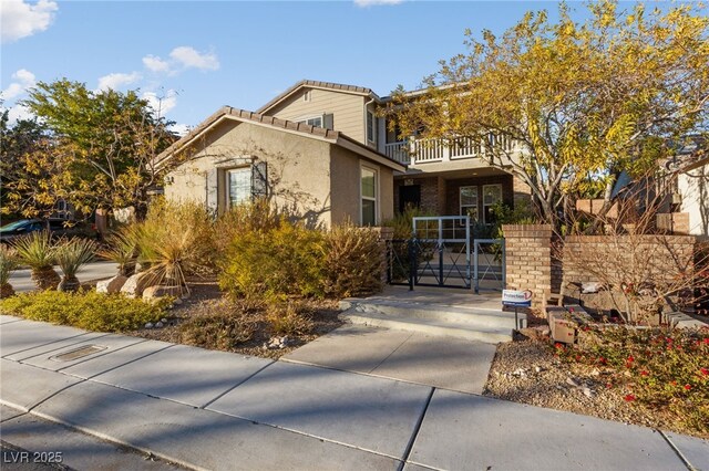 7438 Desertscape Ave, Las Vegas, NV 89178 - view of front of house with a gate, a balcony, stucco siding, and a tile roof