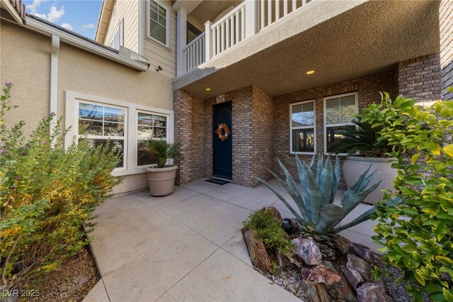 7438 Desertscape Ave, Las Vegas, NV 89178 - property entrance featuring a balcony, stucco siding, and brick siding