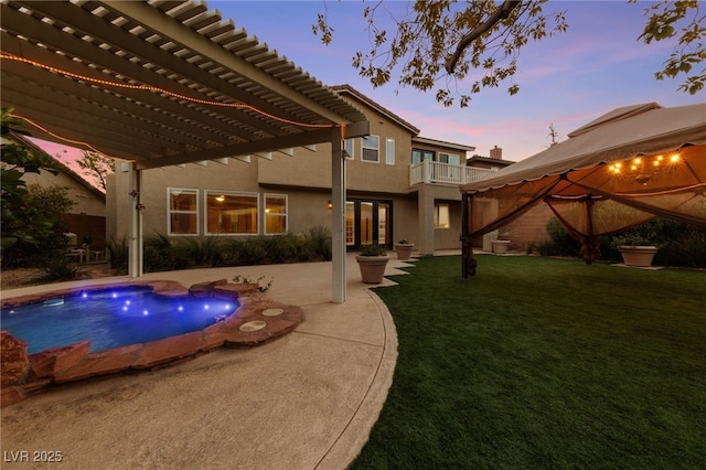 7438 Desertscape Ave, Las Vegas, NV 89178 - back of property at dusk with a pergola, a yard, stucco siding, an outdoor pool, and a balcony