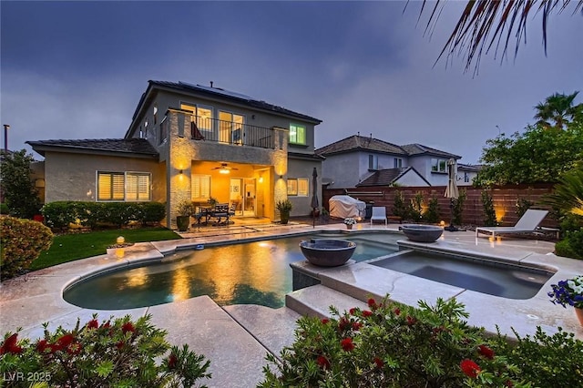 rear view of property with a balcony, a patio area, fence, and stucco siding