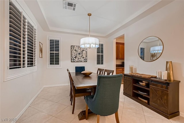 dining space featuring light tile patterned floors, a tray ceiling, and baseboards