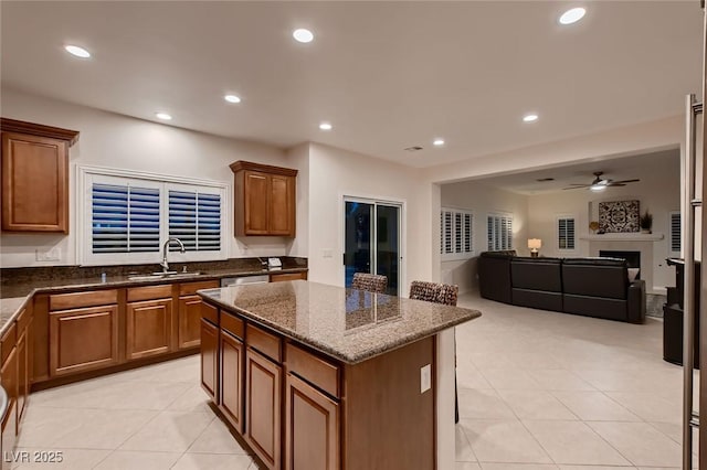 kitchen with a sink, light tile patterned flooring, a kitchen island, brown cabinetry, and recessed lighting