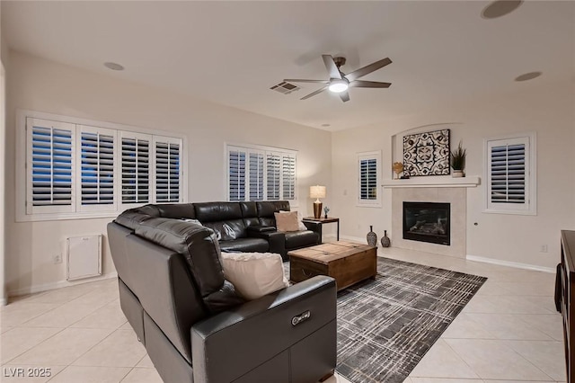 living area featuring a ceiling fan, light tile patterned floors, a fireplace, and baseboards