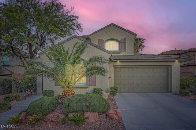 mediterranean / spanish-style home featuring concrete driveway, stucco siding, and an attached garage