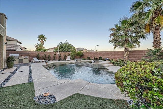 view of swimming pool featuring an outdoor kitchen, a fenced backyard, grilling area, a patio, and a pool with connected hot tub