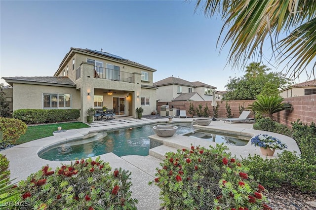 back of house featuring a balcony, a fenced backyard, a patio, stucco siding, and a ceiling fan
