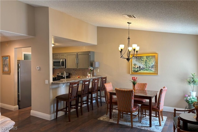 1800 Edmond St Unit 218, Las Vegas, NV 89146 - dining room featuring a chandelier, dark wood finished floors, baseboards, lofted ceiling, and a textured ceiling