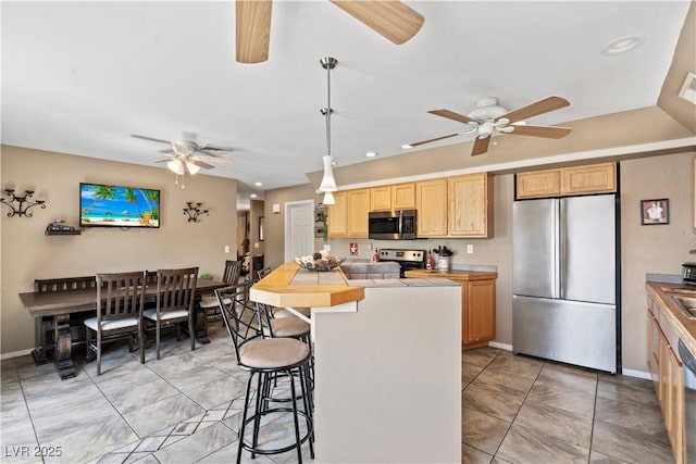 3661 Margarita Way, Las Vegas, NV 89103 - kitchen featuring stainless steel appliances, a ceiling fan, a kitchen bar, light brown cabinetry, and recessed lighting