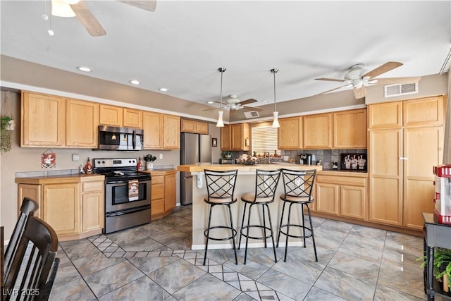 3661 Margarita Way, Las Vegas, NV 89103 - kitchen with appliances with stainless steel finishes, ceiling fan, light brown cabinets, a kitchen breakfast bar, and a kitchen island
