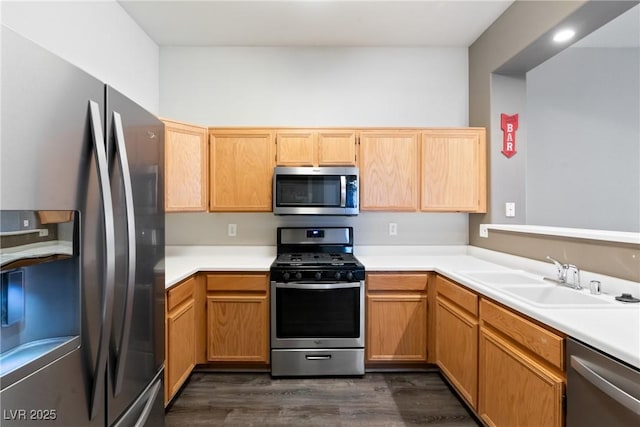 kitchen featuring appliances with stainless steel finishes, a sink, dark wood finished floors, and light countertops