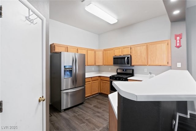 kitchen with stainless steel appliances, a peninsula, dark wood-type flooring, and light countertops