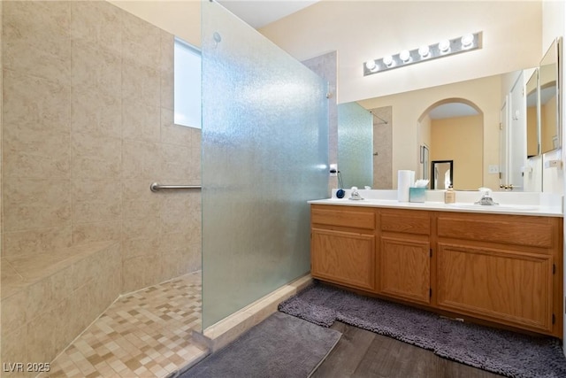 bathroom with a walk in shower, wood finished floors, and double vanity