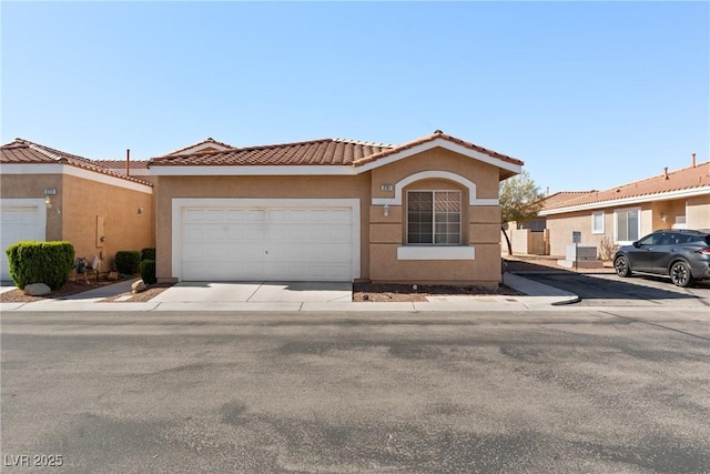 view of front of home with stucco siding, a tiled roof, an attached garage, and concrete driveway