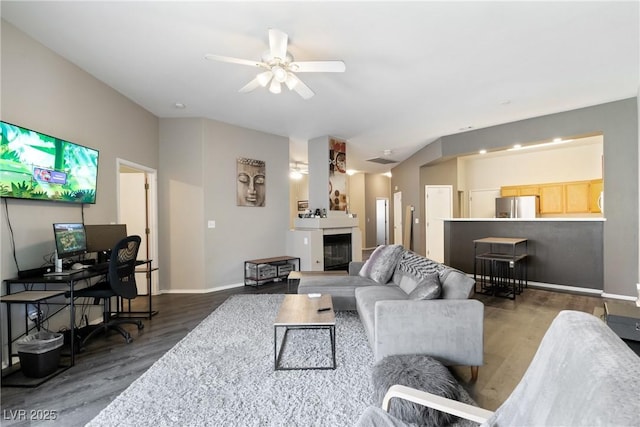 living room with wood finished floors, a ceiling fan, a glass covered fireplace, and baseboards