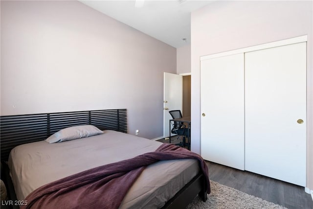 bedroom with wood finished floors, a closet, and a towering ceiling