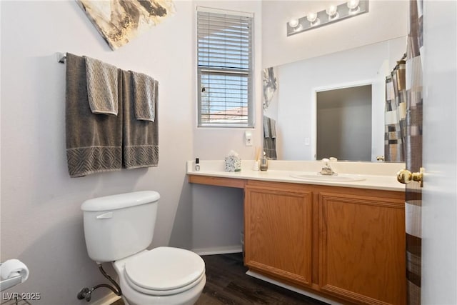 bathroom with toilet, vanity, baseboards, and wood finished floors