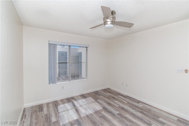 spare room with light wood finished floors, a textured ceiling, ceiling fan, and baseboards