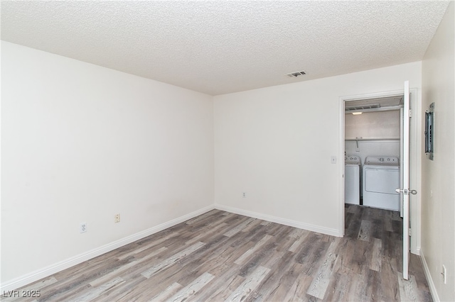 unfurnished bedroom featuring washer and dryer, wood finished floors, a textured ceiling, and baseboards