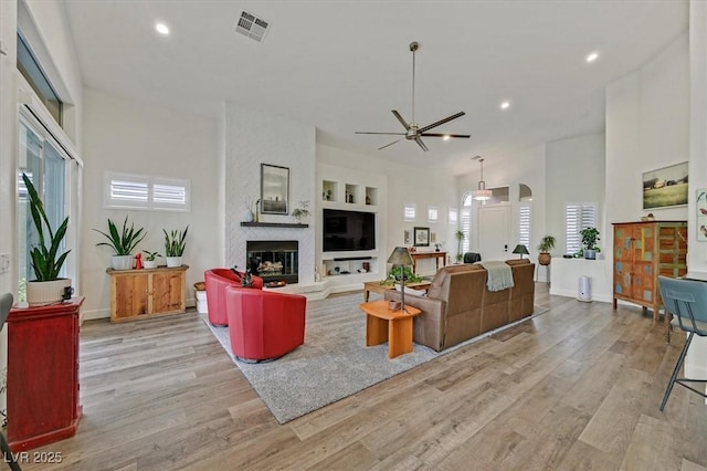 512 Pima Canyon Ct, Las Vegas, NV 89144 - living room with light wood finished floors, ceiling fan, a large fireplace, recessed lighting, and a high ceiling
