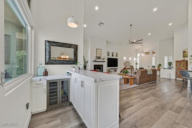512 Pima Canyon Ct, Las Vegas, NV 89144 - kitchen with beverage cooler, a peninsula, white cabinetry, light wood-style flooring, and a ceiling fan