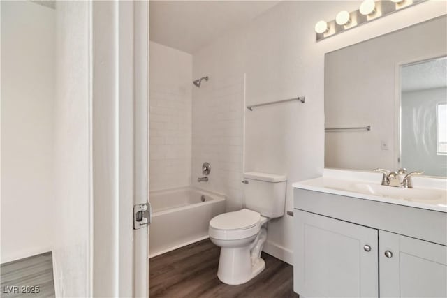 bathroom featuring toilet, wood finished floors, vanity, and shower / washtub combination