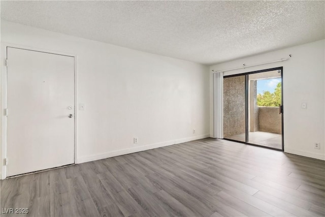 spare room featuring wood finished floors, a textured ceiling, and baseboards