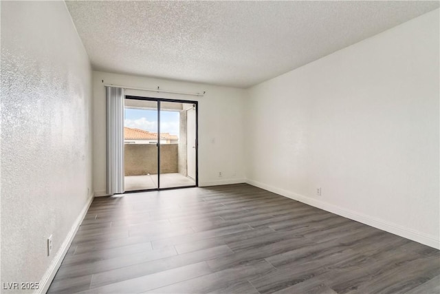 spare room featuring dark wood-type flooring, a textured ceiling, and baseboards