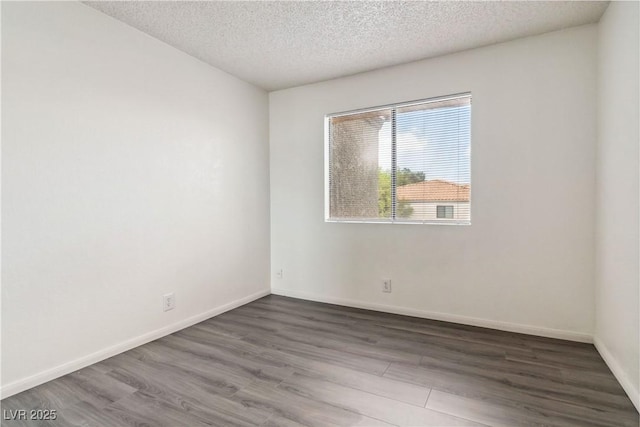 unfurnished room featuring wood finished floors, a textured ceiling, and baseboards
