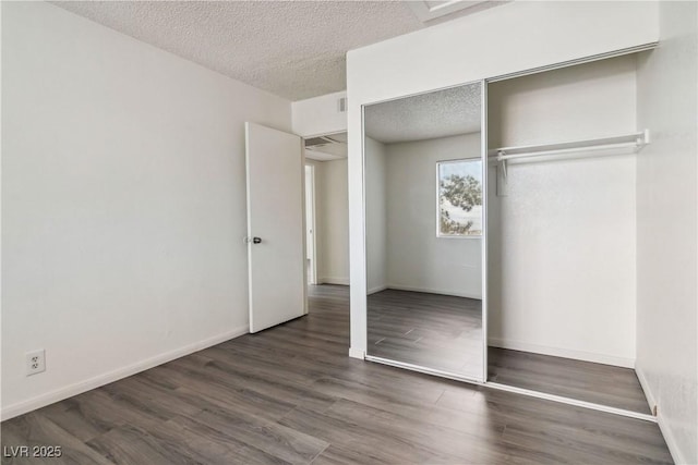 unfurnished bedroom featuring a textured ceiling, wood finished floors, a closet, and baseboards
