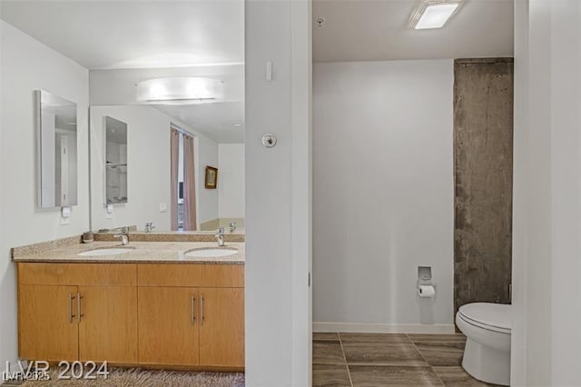 full bathroom with toilet, double vanity, and baseboards