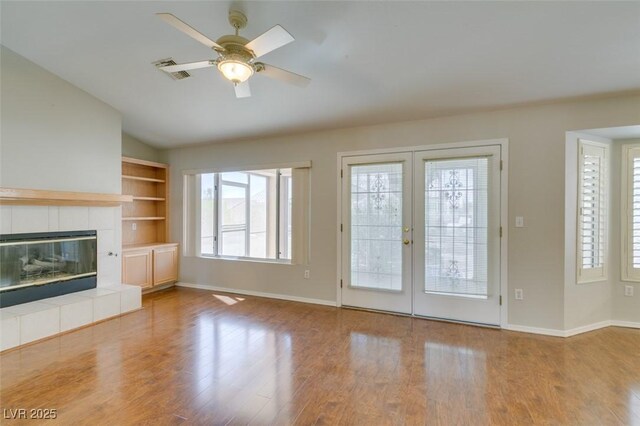 10009 Netherton Dr, Las Vegas, NV 89134 - unfurnished living room with baseboards, a tiled fireplace, french doors, wood finished floors, and vaulted ceiling