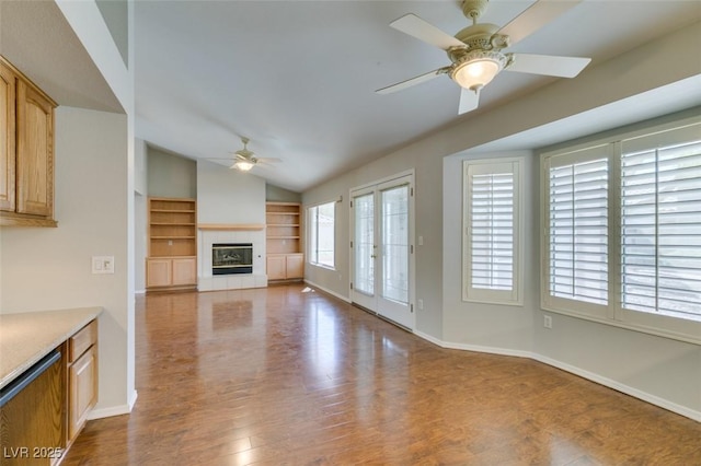 10009 Netherton Dr, Las Vegas, NV 89134 - unfurnished living room featuring a ceiling fan, lofted ceiling, a tiled fireplace, wood finished floors, and baseboards