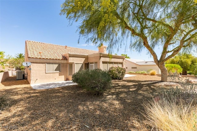 10009 Netherton Dr, Las Vegas, NV 89134 - back of property featuring a tile roof, stucco siding, a chimney, and central AC unit