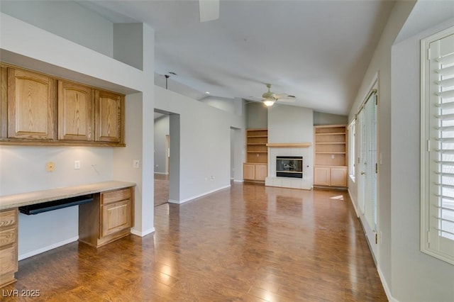 10009 Netherton Dr, Las Vegas, NV 89134 - unfurnished living room featuring a ceiling fan, lofted ceiling, dark wood-style floors, a tile fireplace, and baseboards